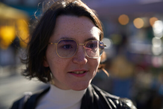 Woman with glasses smiling outdoors in soft focus urban background. Brussels, Belgium