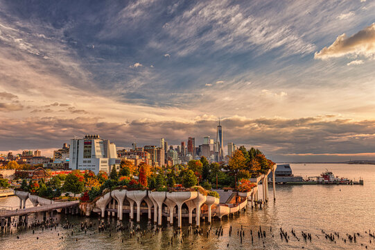 Aerial view of a cityscape with an elevated park surrounded by water at sunset.  Little Island Park, New York City, USA