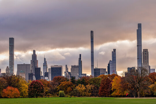 Autumn skyline of a city with clouded sky and colorful trees in the foreground. Central Park, New York City, USA