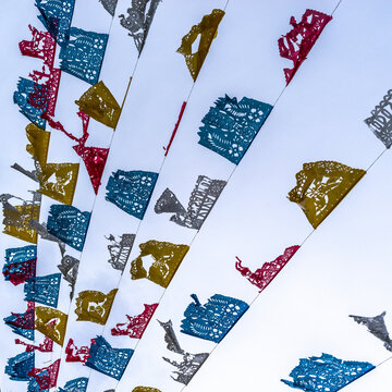 Colorful paper flags in blue, red, and yellow strung against a clear sky. Todos Santos, Baja California, Mexico