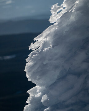 Jagged ice formation with a blurred mountainous background at dusk. Big White Mountain, British Columbia, Canada