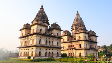 Obraz premium Golden hour view of historic Royal cenotaphs of Orchha with dramatic clouds and soft light, Madhya Pradesh, India.