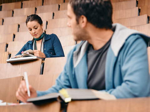Two students studying in a college lecture hall with notebooks and focus on their work. Germany