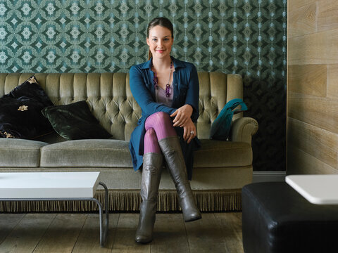 Woman sitting on a vintage sofa in a stylish living room with patterned wallpaper. Germany
