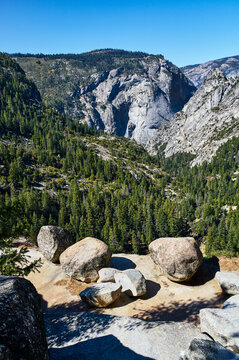 Scenic mountain landscape with rocky terrain and lush green forest under a clear blue sky. Yosemite National Park, California, USA