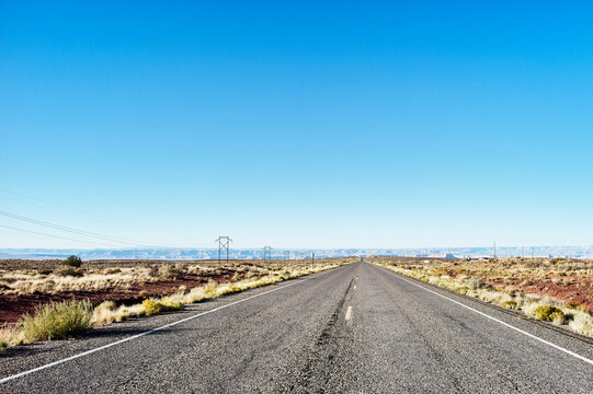 Endless straight road in a desert landscape under clear blue sky. Arizona, USA