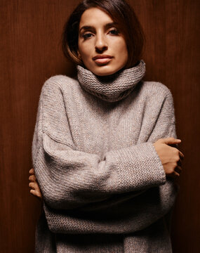 Woman in a cozy turtleneck sweater standing against a wooden backdrop Germany