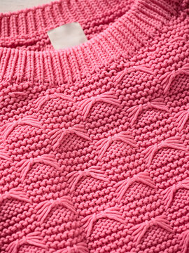 Pink knitted sweater with intricate textured patterns and ribbed collar. Germany