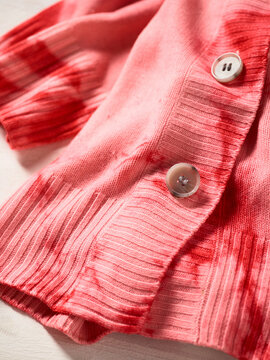 Close-up of a pink ribbed cardigan with red tie-dye accents and large buttons. Germany