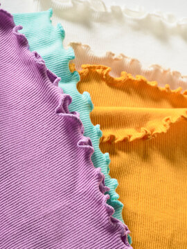 Colorful fabric swatches with ruffled edges in purple, teal, orange, and cream.  Germany