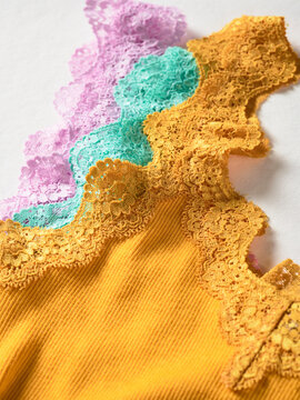 Lace fabric in vibrant yellow, green, and purple layered on white surface. Germany