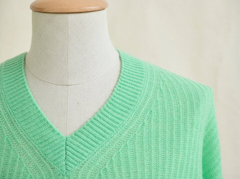 Mannequin displaying a mint green V-neck sweater against a neutral background. Germany