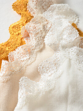 Fabric with lace trims in white, cream, and mustard color on a textured surface. Germany
