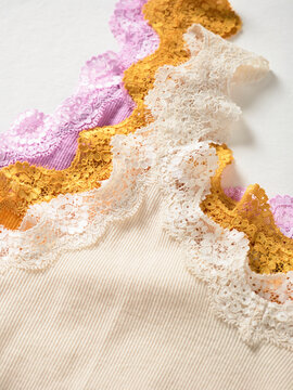 Colorful lace fabric layers in pastel hues arranged in a wavy pattern on a textured surface. Germany
