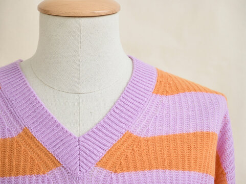 Knitted mannequin wearing a lavender and orange striped V-neck sweater. Germany