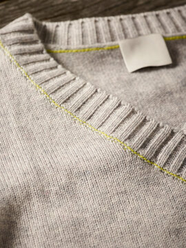 Beige sweater with ribbed neckline and subtle green stitching detail. Germany