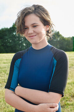 Smiling young woman in blue sports top amidst a lush outdoor setting under bright sky. Baltic Sea, Germany