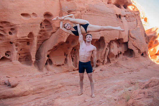 Acrobatic duo performs stunts against a backdrop of rugged red rock formations. WA, USA