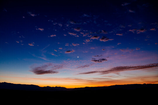 Vibrant sunset with colorful sky transitioning from orange to deep blue over a mountainous horizon. WA, USA
