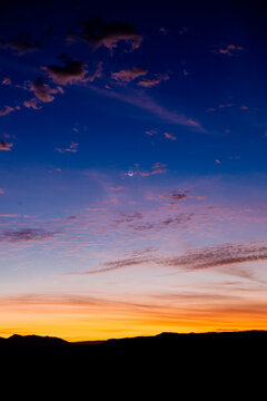 Vibrant sunset with deep blue and orange hues over distant mountain silhouettes. WA, USA