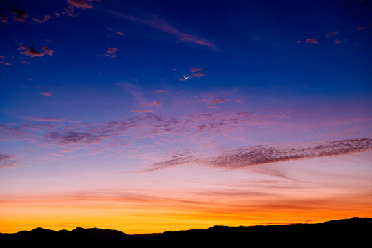 Vibrant sunset sky with vivid blue, pink, and orange hues over silhouetted mountains. WA, USA