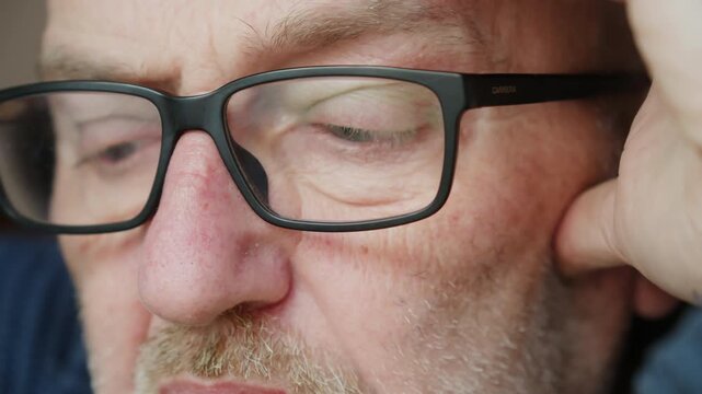 Tight macro shot of a mans eyes darting as he reads, with light reflecting off his spectacles. Focus on technical data and visual information processing.