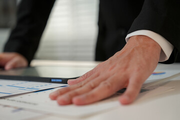 Obraz premium In a modern office, business people are working on laptops. Men in black suits are working and typing on laptop keyboards at their desks.