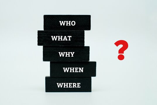 A stack of coloured blocks featuring the "5 Ws" (WHO, WHAT, WHY, WHEN, WHERE) next to a red question mark. Representation of investigative journalism, root cause analysis and strategic inquiry