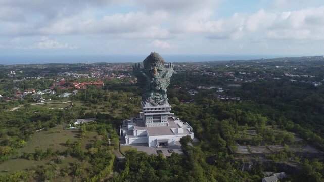 Aerial drone orbiting right around the monumental Garuda Wisnu Kencana statue in Bali, Indonesia.