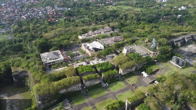 Aerial drone moving backward revealing the vast Garuda Wisnu Kencana Cultural Park complex in Bali, Indonesia.