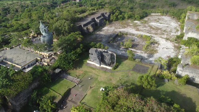 Cinematic aerial drone orbiting left above Plaza Garuda at Garuda Wisnu Kencana Cultural Park in Bali, Indonesia.
