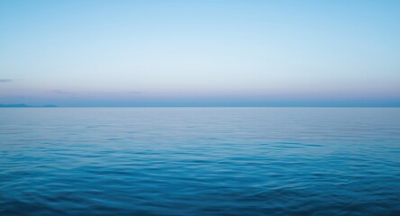 Fototapeta premium Quiet seascape at dusk with smooth ocean surface and translucent blue sky with copy space
