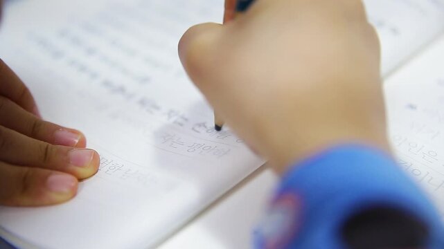 INCHEON, SOUTH KOREA - MARCH 17, 2026: Close-up of a Child&rsquo;s Hands Transcribing Bible Verses in Korean in a Notebook