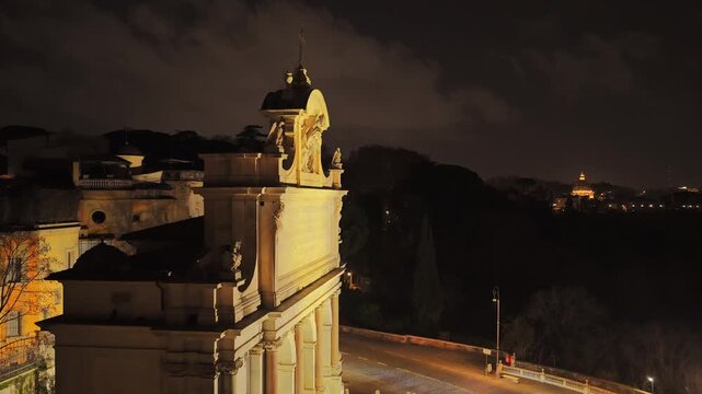 Aerial drone shot of the side of the illuminated Fontanone on the Janiculum with the distant dome of St. Peter's Basilica at night, Rome, Italy, Europe