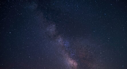 Fototapeta premium Night sky long exposure showing swirling Milky Way and scattered stars amid cosmic dust with grain