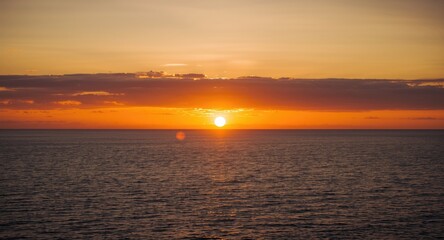 Obraz premium Glorious sundown casting radiant gold over vast sea framed by impressive cloud layers