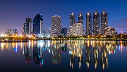 Fototapeta premium Modern city skyline with sleek skyscrapers and vibrant night reflections on calm lake water