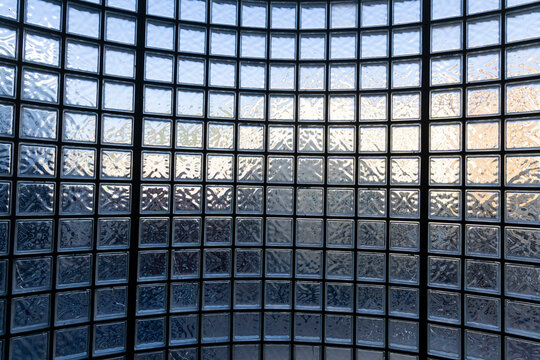 Contemporary architectural interior featuring a large curved glass block wall illuminated by natural light.