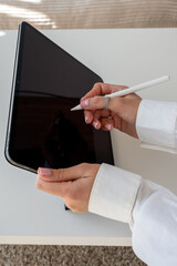 Close-up of female hands using a stylus on a digital tablet, digital drawing and creative work concept, isolated on white background © Juli