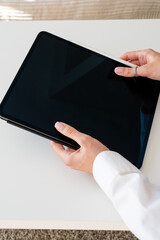Two female hands in a shirt holding a digital tablet on a white background, technology and digital work concept, workspace © Juli