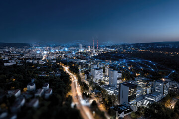 Obraz premium An aerial view of a bustling city at night, showcasing illuminated skyscrapers and connected networks that represent modern urban life and technological advancement.