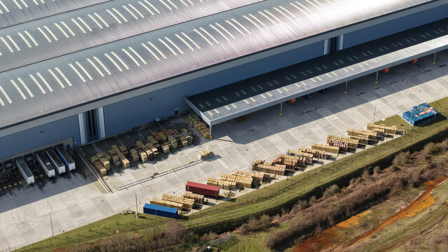 Aerial view of industrial warehouses and a fleet of trucks form a geometric dance of commerce, juxtaposed against the raw earth, Doncaster, United Kingdom.