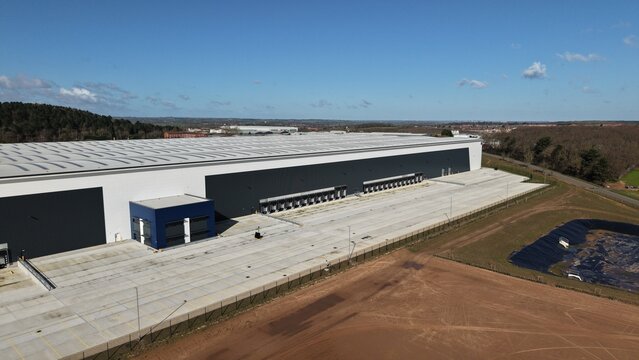 Aerial view of the sprawling warehouse casts a long shadow, its clean lines contrasting with the wild, earthy tones of the surrounding landscape, Doncaster, United Kingdom.
