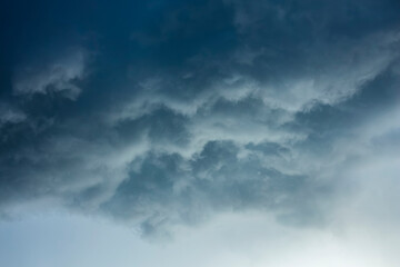 Obraz premium Clouds gather in the sky during late afternoon, blocking sunlight and creating a dark atmosphere. The weather may change soon as the clouds build up.