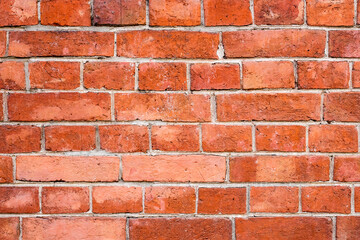 Obraz premium A wall made of red bricks shows a rough texture and various patterns. The bricks are placed closely with some gaps. This structure can be seen in many urban areas
