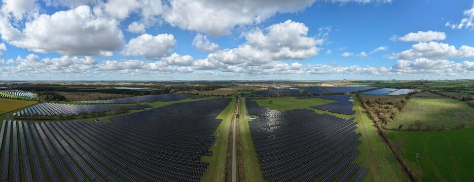 Aerial view of Tiln Battery Energy Storage System with solar panels basking under a partly cloudy sky, Retford, United Kingdom.