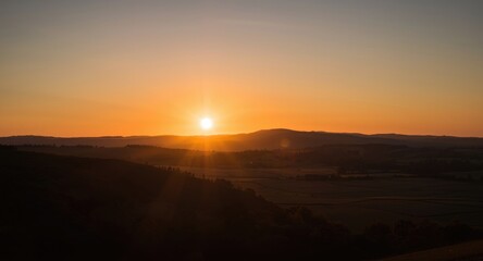 Obraz premium Sunset casting long shadows on rolling hills and rural fields