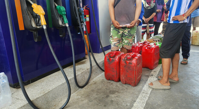 Crowd queuing at a gas station with fuel containers during a fuel shortage. People waiting to refill gasoline reflects energy crisis, demand, real-life situation
