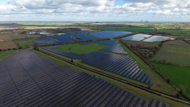 Aerial view of expansive solar panels gleaming under the sun, contrasting with the surrounding verdant fields, Tiln Battery Energy Storage System, Retford, United Kingdom.