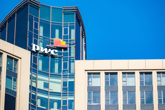 PwC logo on glass facade, high-rise glass office building against blue sky, finance and consulting, global economy, professional financial services in Germany, Frankfurt - February 9, 2025